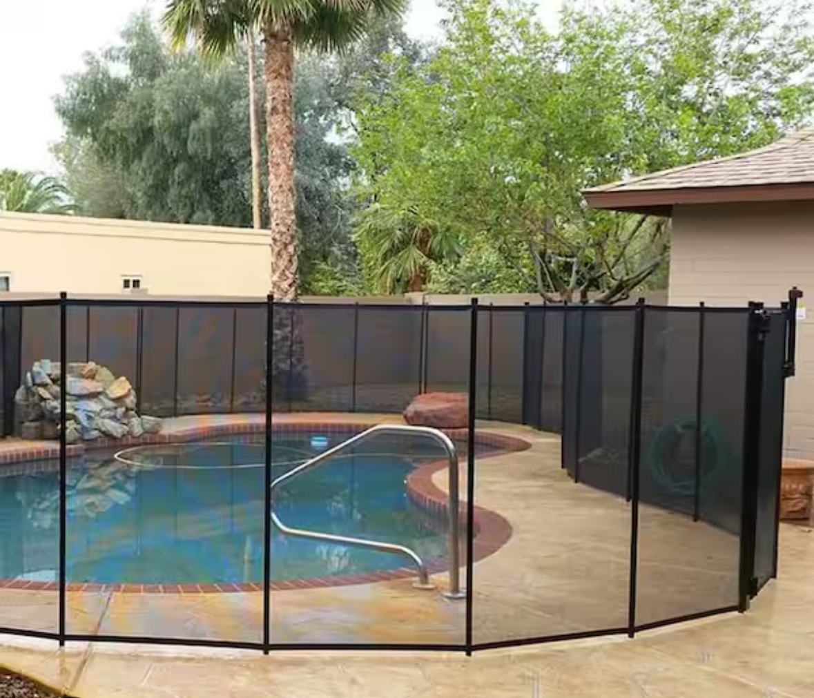 Black mesh pool safety fence around a backyard pool and spa